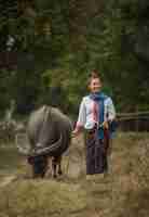 Foto gratuita una mujer camina sosteniendo una cuerda de búfalo en el prado.