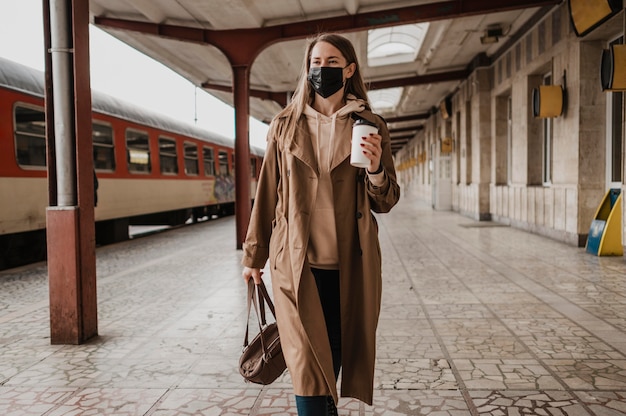 Foto gratuita mujer caminando con un café en una estación de tren