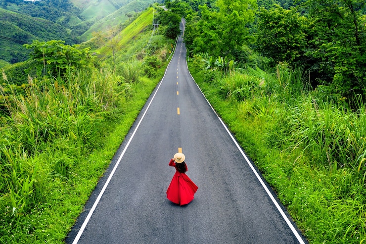 Foto gratuito mujer caminando por la carretera del cielo sobre la cima de las montañas con selva verde en la provincia de nan, tailandia