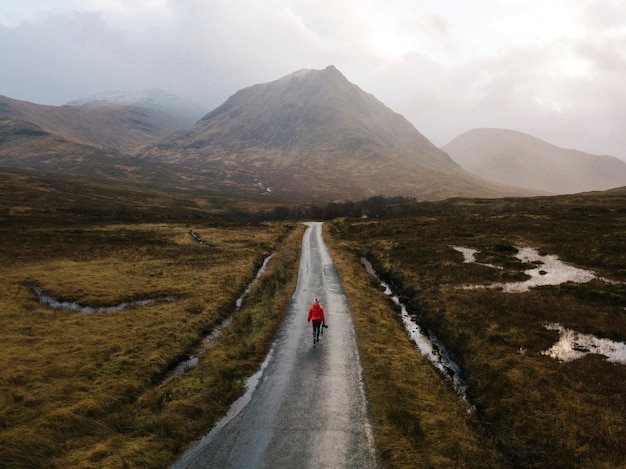 Foto gratuita mujer caminando por una carretera en glen etive, escocia