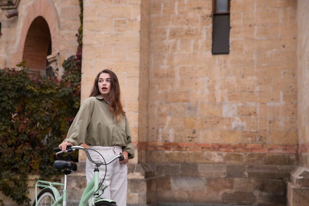 Mujer caminando junto a la bicicleta al aire libre con espacio de copia