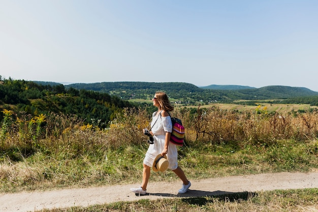 Mujer caminando de lado con paisaje como fondo