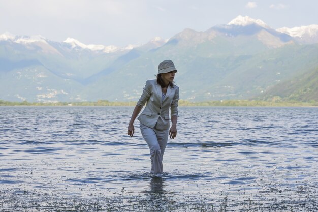 Mujer caminando en el lago con altas montañas de fondo