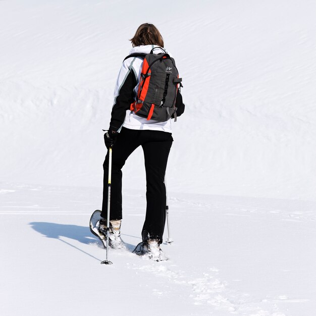 Mujer caminando en la nieve con raquetas