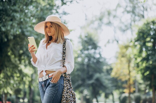 Mujer caminando en el parque y hablando por teléfono