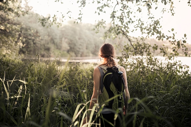 Foto gratuita mujer caminante caminando en la hierba verde cerca del lago