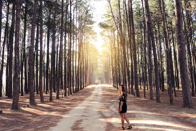 Mujer en un camino de tierra con árboles a los lados