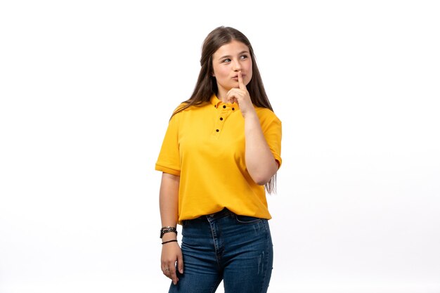 mujer en camisa amarilla y pantalones vaqueros azules posando con expresión de pensamiento sobre el fondo blanco ropa modelo mujer