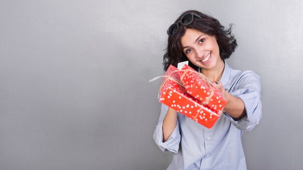 Mujer en camisa azul dando caja de regalo