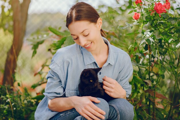 Mujer en una camisa azul jugando con lindo gatito