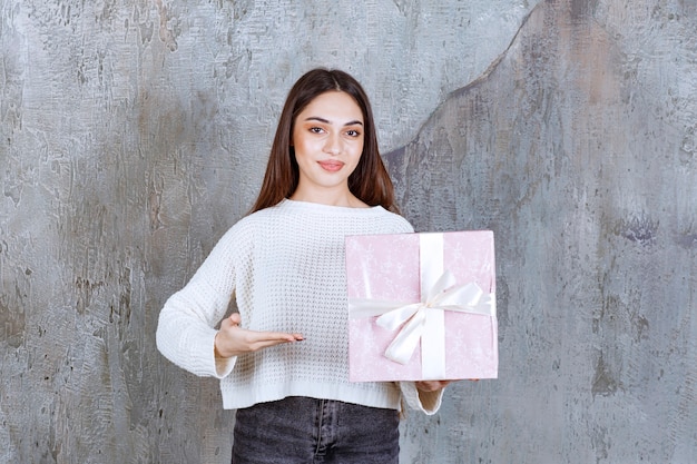 mujer con camisa blanca sosteniendo una caja de regalo de color púrpura.