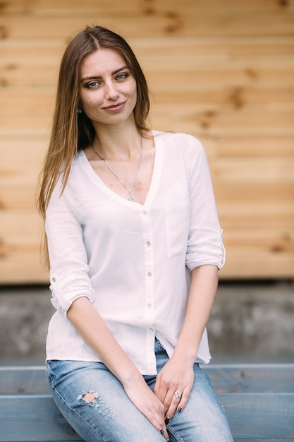 Mujer con una camisa blanca y vaqueros sentada