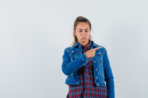 Mujer en camisa, chaqueta apuntando hacia el lado derecho y mirando molesta, vista frontal.