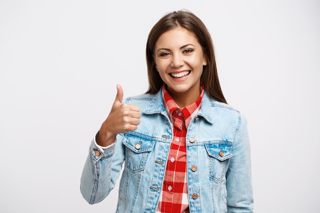 Foto gratuita mujer en camisa a cuadros y chaqueta vaquera muestra el pulgar hacia arriba