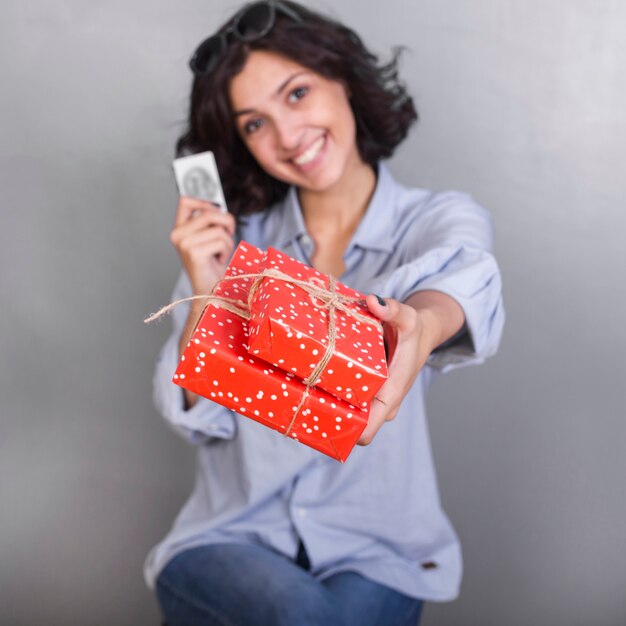 Mujer en camisa dando caja de regalo