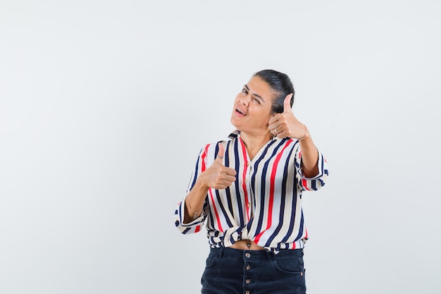 Foto gratuita mujer en camisa, falda mostrando doble pulgar hacia arriba y mirando confiada