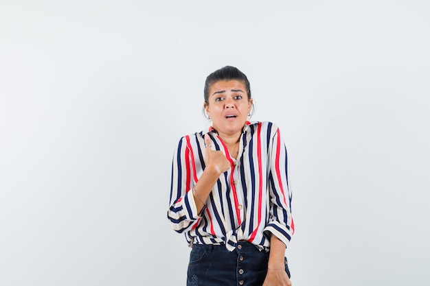 Foto gratuita mujer en camisa, falda mostrándose de manera inquisitiva y mirando perpleja