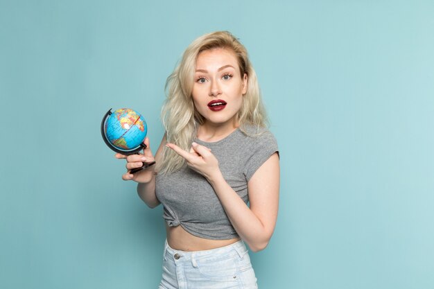 mujer en camisa gris y jeans azul brillante sosteniendo un pequeño globo