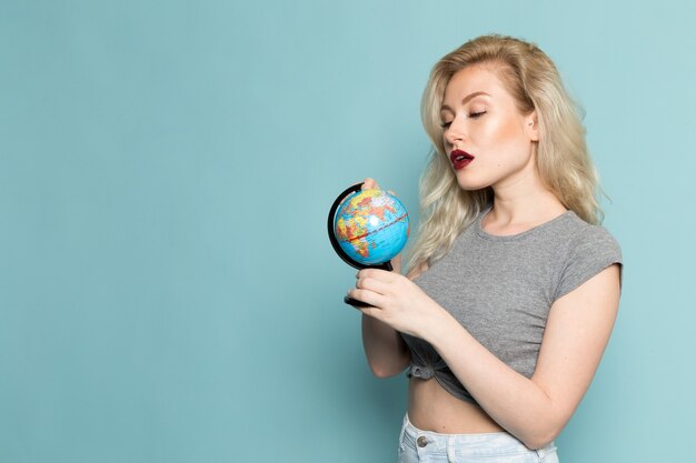 mujer en camisa gris y jeans azul brillante sosteniendo un pequeño globo