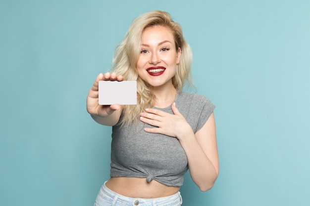 Mujer en camisa gris y jeans azul brillante con tarjeta blanca