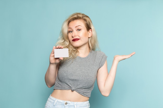 Mujer en camisa gris y jeans azul brillante con tarjeta blanca