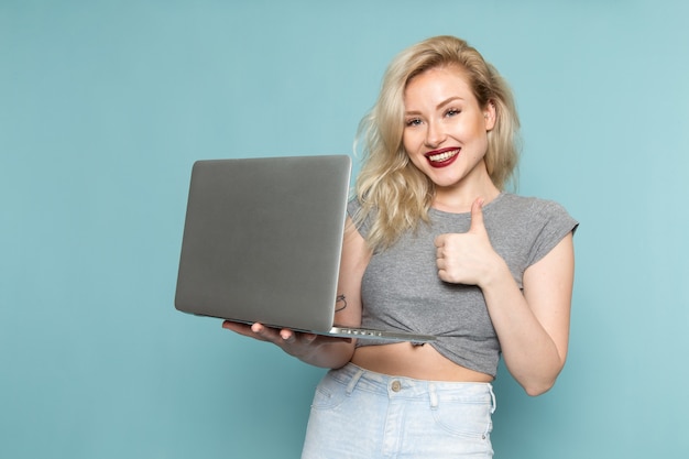 Mujer en camisa gris y jeans azul brillante usando laptop