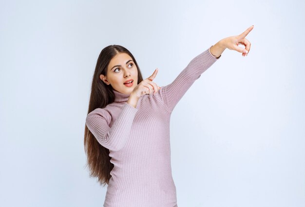 mujer con camisa morada mostrando algo arriba.