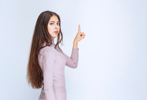 mujer con camisa morada mostrando algo arriba.