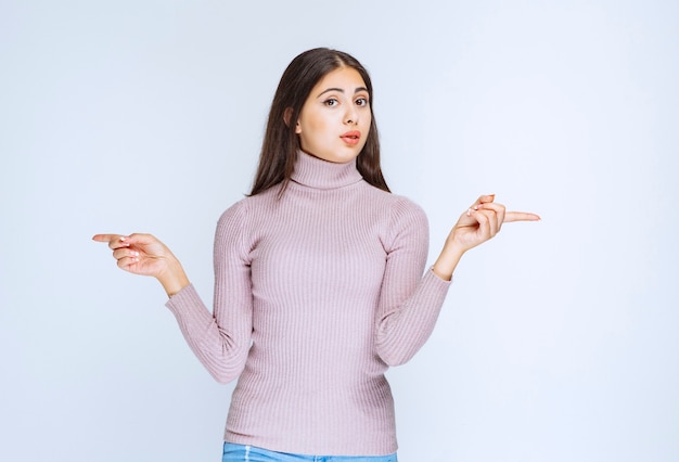 mujer con camisa morada mostrando algo a la izquierda.