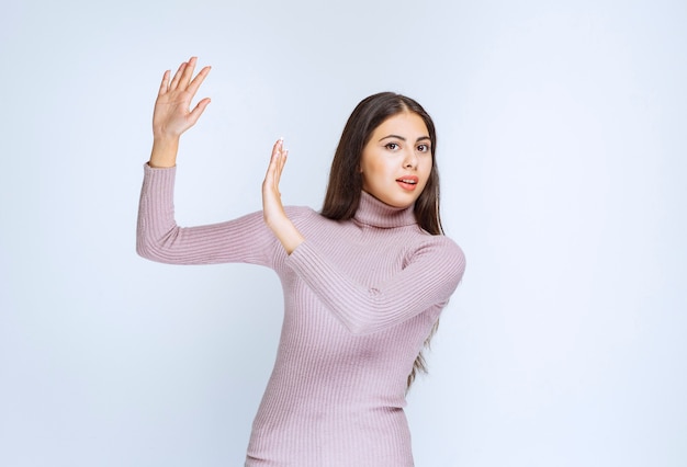 mujer en camisa morada parando algo con las manos.