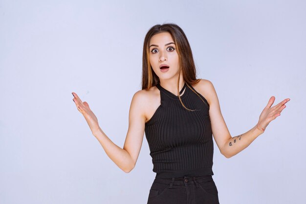 Mujer en camisa negra haciendo presentación con las manos abiertas.