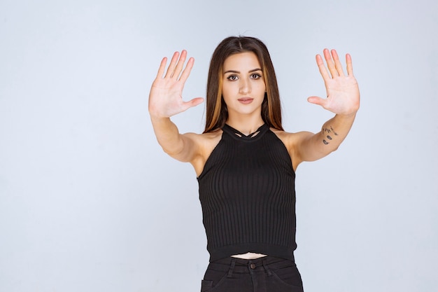 Foto gratuita mujer en camisa negra haciendo señal de stop.