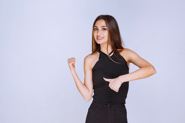 Mujer en camisa negra mostrando el pulgar hacia arriba signo.