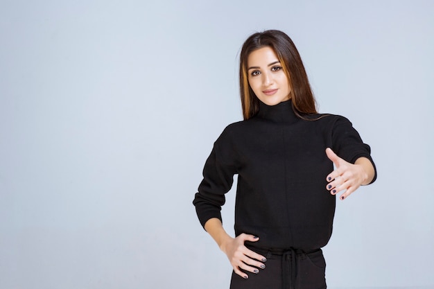 mujer en camisa negra mostrando signo de mano positivo.