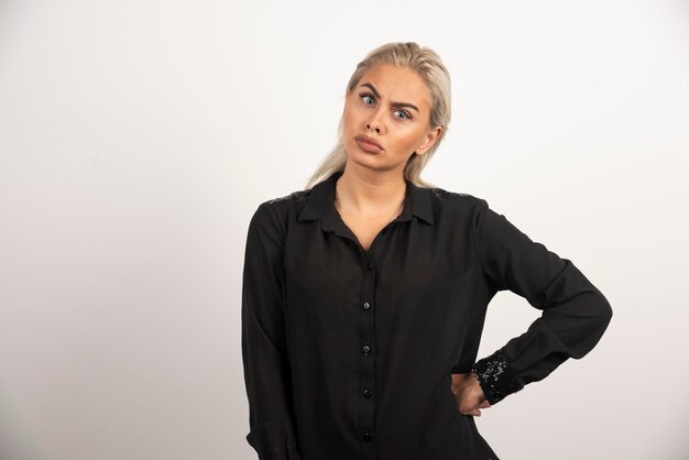 Mujer en camisa negra posando sobre fondo blanco. Foto de alta calidad