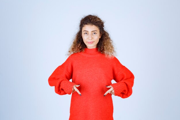 mujer con camisa roja apuntando a algo debajo.