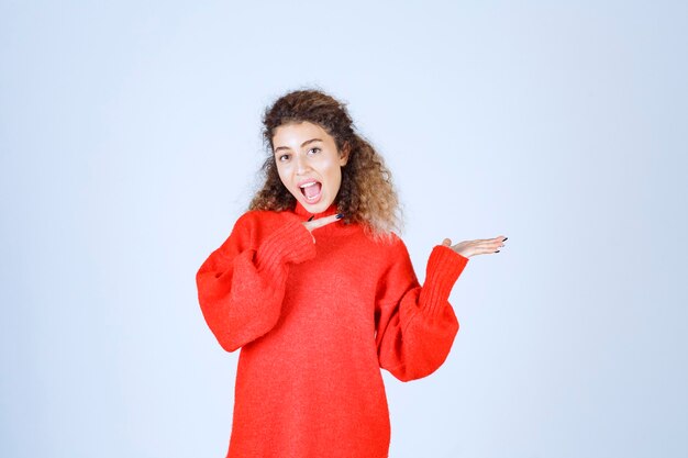 mujer con camisa roja apuntando a alguien de la derecha.