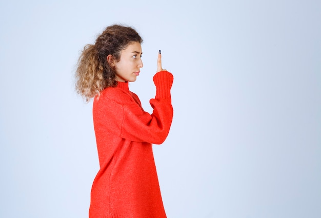 mujer con camisa roja apuntando a alguien o en algún lugar con cara emocional en azul.