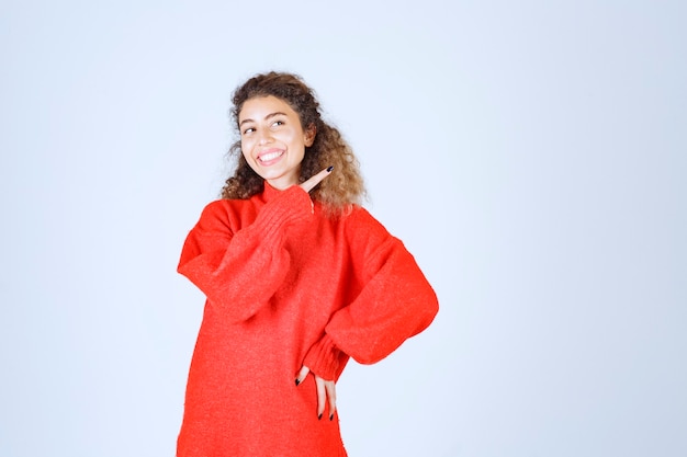 mujer con camisa roja apuntando a alguien o en algún lugar con cara emocional en azul.