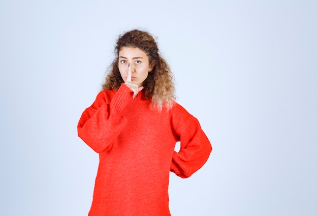 Foto gratuita mujer con una camisa roja pidiendo silencio.