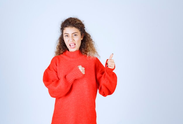 mujer en camisa roja que muestra como signo de mano.