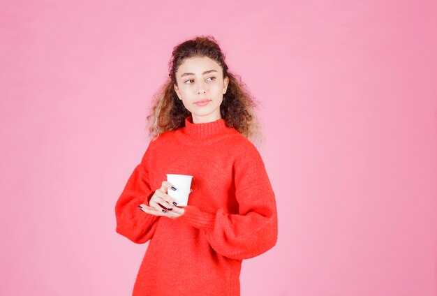 mujer en camisa roja sosteniendo una taza de café desechable.