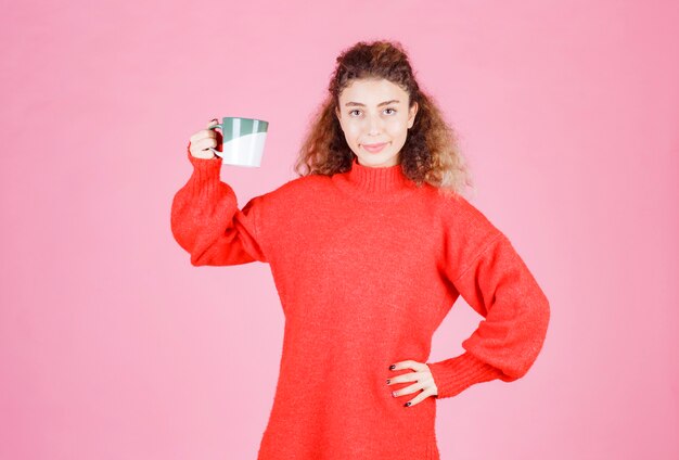 mujer de camisa roja sosteniendo una taza de café.