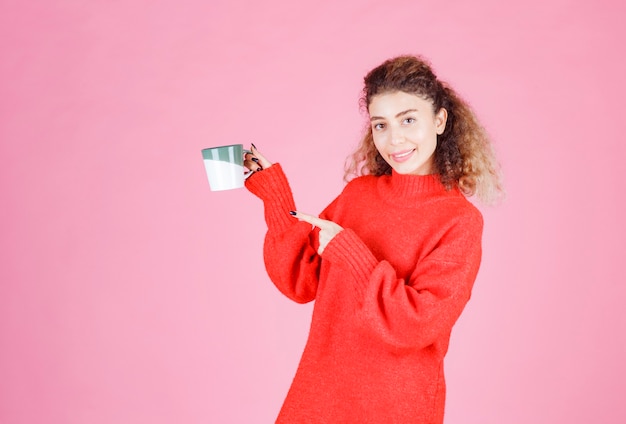mujer de camisa roja sosteniendo una taza de café.