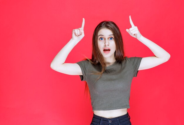 Mujer con camisa verde apuntando a algo arriba.