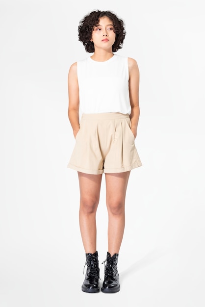Foto gratuita mujer en camiseta blanca sin mangas y pantalones cortos beige con ropa de verano de espacio de diseño