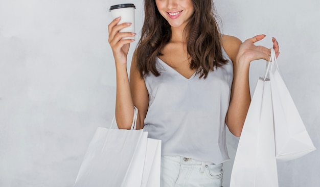 Foto gratuita mujer en camiseta con bolsas de compras y café