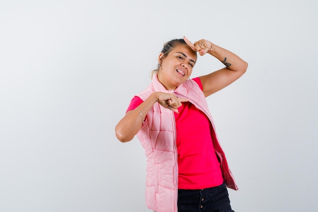 Mujer en camiseta, chaleco apuntando con el dedo y mirando alegre