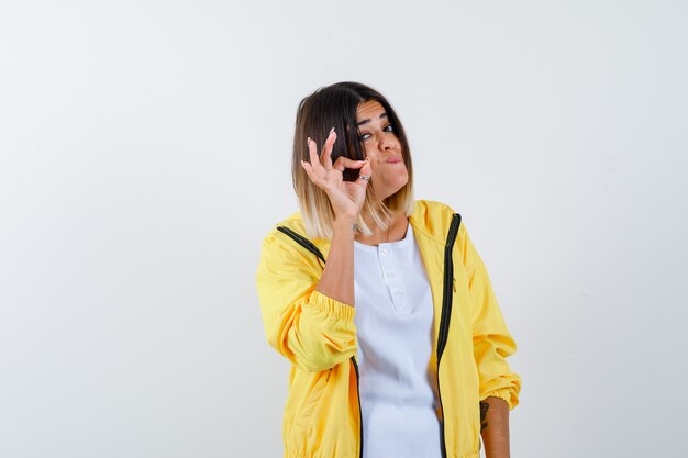 Mujer en camiseta, chaqueta mostrando un gesto aceptable y mirando confiado, vista frontal.