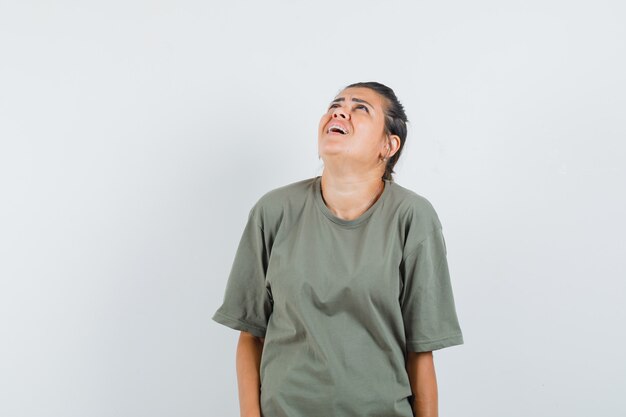 mujer en camiseta mirando hacia arriba y luciendo optimista